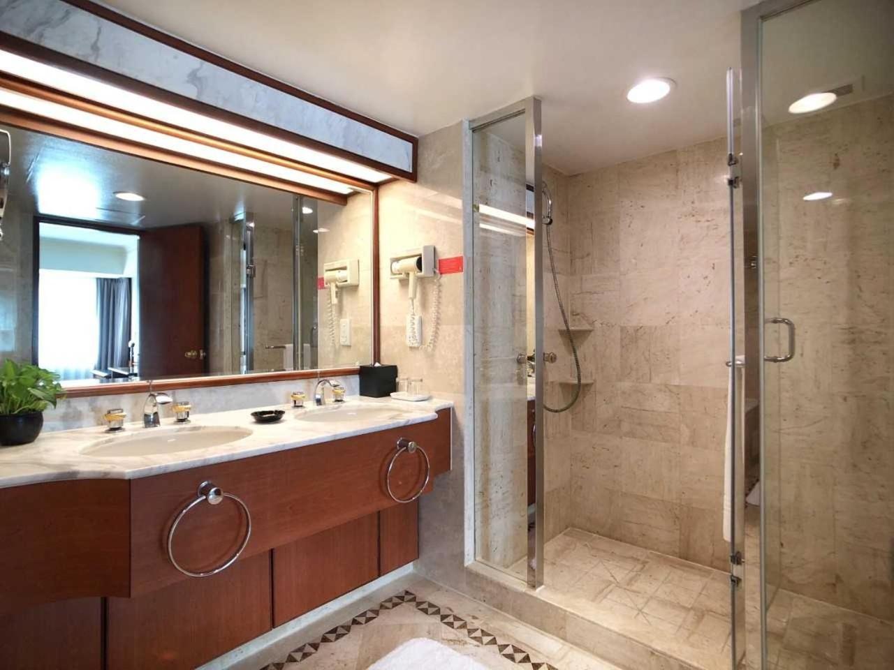 Evergreen Laurel Hotel - Taichung Eksteriør bilde The photo depicts a modern bathroom featuring a double vanity sink with a marble countertop and wooden cabinetry. Above the sinks, there is a large mirror with integrated lighting. To one side, there is a shower enclosed in glass, showcasing a sleek 