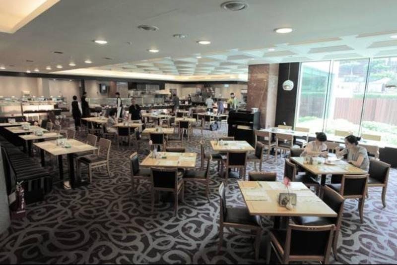 Evergreen Laurel Hotel - Taichung Eksteriør bilde The photo shows a spacious restaurant or dining area with a modern interior design. There are several tables arranged throughout the room, some of which are set for dining while others appear to be empty. The decor includes a patterned carpet and lar
