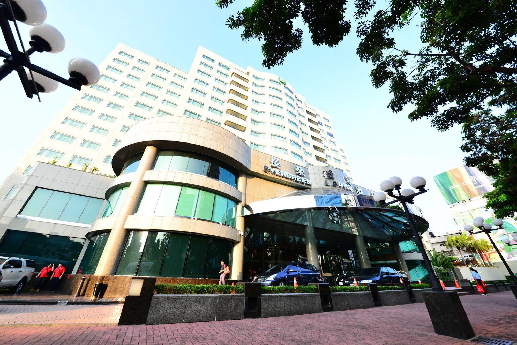 Evergreen Laurel Hotel - Taichung Eksteriør bilde The photo shows a modern multi-story building, which appears to be a hotel or commercial establishment. The structure has a rounded glass entrance with a distinctive architectural design, featuring large windows. The building is surrounded by greener