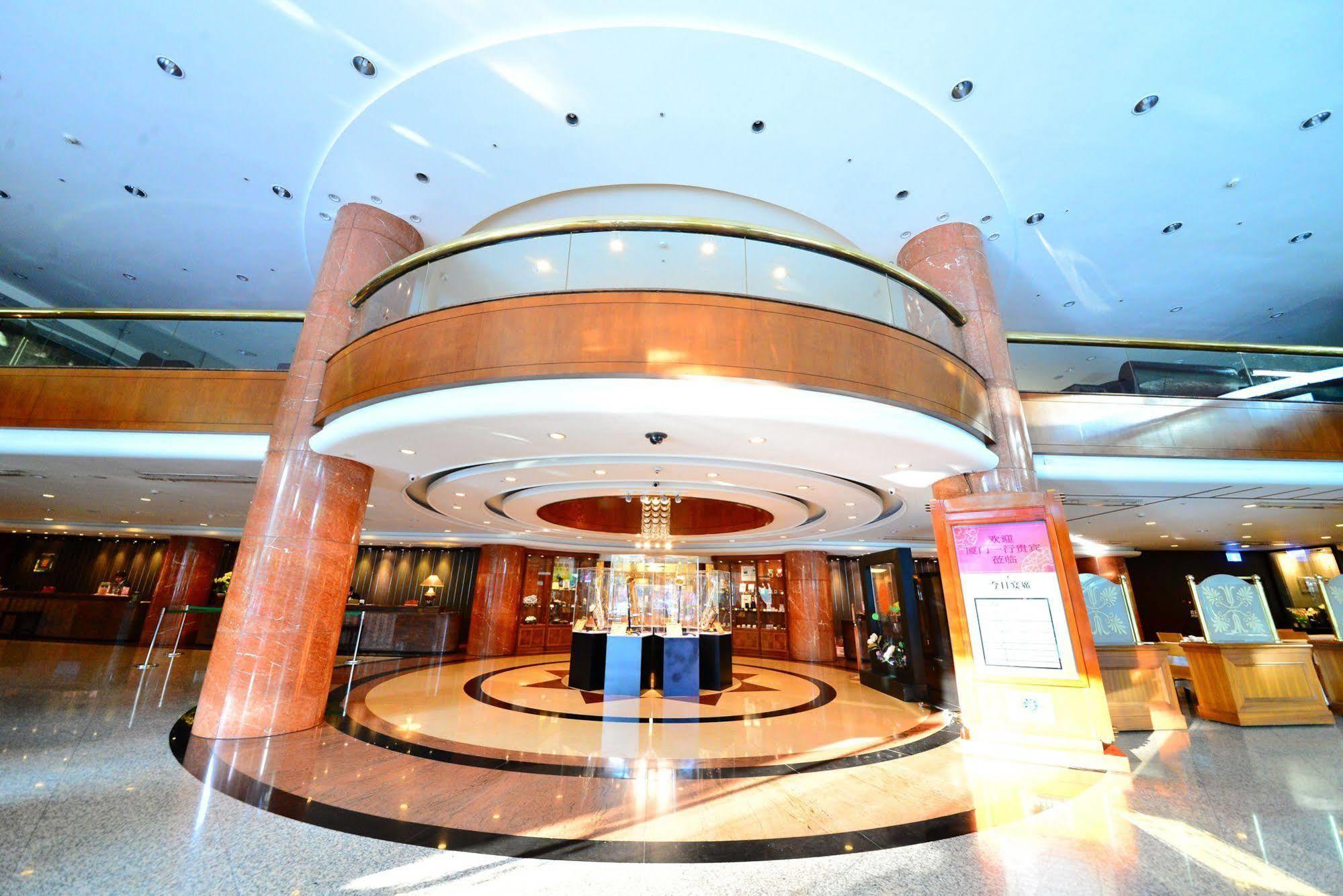 Evergreen Laurel Hotel - Taichung Eksteriør bilde The photo shows the interior of a spacious lobby area. It features a modern architectural design with polished surfaces and a circular ceiling structure. The walls are accented with wooden panels, and there is a central chandelier hanging from the ce