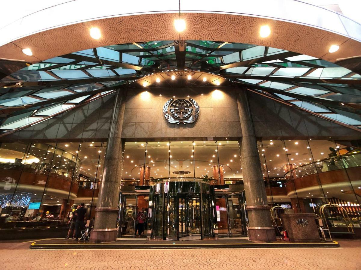 Evergreen Laurel Hotel - Taichung Eksteriør bilde The image shows the entrance of a modern building, likely a hotel or a luxury establishment. The entrance features a large revolving door surrounded by glass panels. Above the entrance, there is a prominent logo or emblem. The overall architectural d