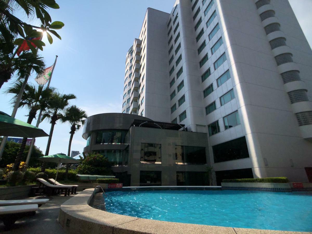 Evergreen Laurel Hotel - Taichung Eksteriør bilde The photo depicts a hotel or residential building alongside a swimming pool. The pool is situated in the foreground, with a curved section of the building visible behind it. Surrounding the pool, there are lounge chairs for relaxation. In the backgro