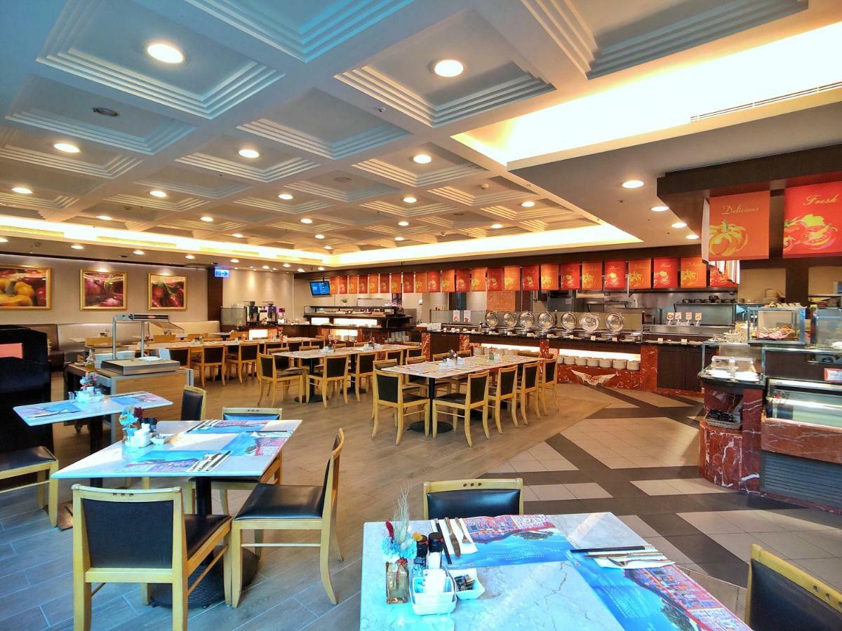 Evergreen Laurel Hotel - Taichung Eksteriør bilde The photo shows the interior of a restaurant. The dining area features several tables with chairs arranged neatly. The flooring has a contemporary design, and the ceiling is structured with a coffered pattern. There is a buffet area along one wall wi