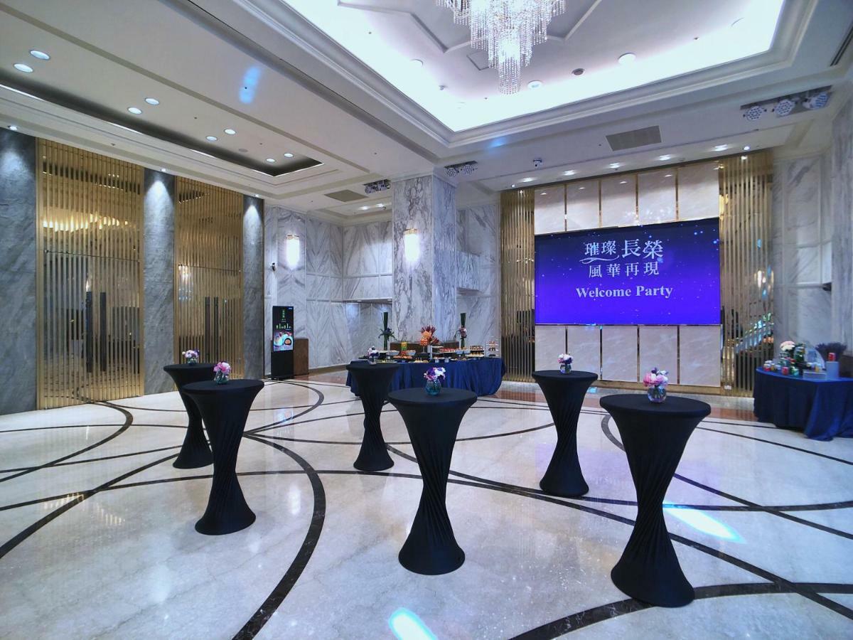 Evergreen Laurel Hotel - Taichung Eksteriør bilde The photo depicts a spacious and elegantly decorated event space, likely set up for a welcome party. The room features polished marble flooring and tall ceilings, giving it a sophisticated atmosphere. In the center, several round tables with black ta
