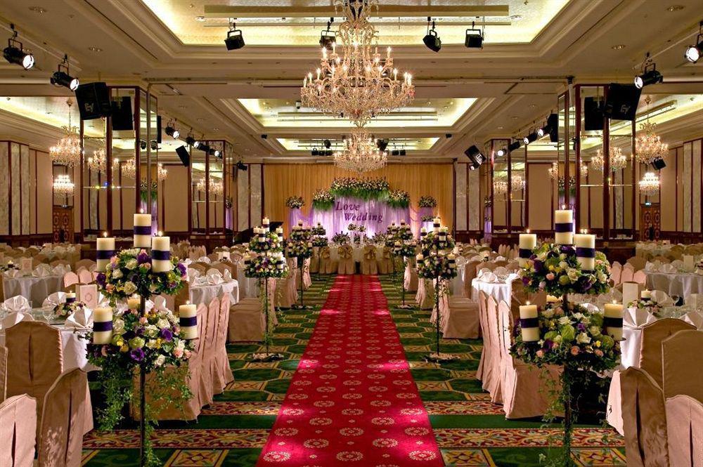 Evergreen Laurel Hotel - Taichung Eksteriør bilde The photo shows an elegantly decorated banquet hall set up for a wedding or formal event. The center aisle is lined with rows of elegantly draped chairs and features a bright red carpet. On either side of the aisle, there are beautifully arranged flo