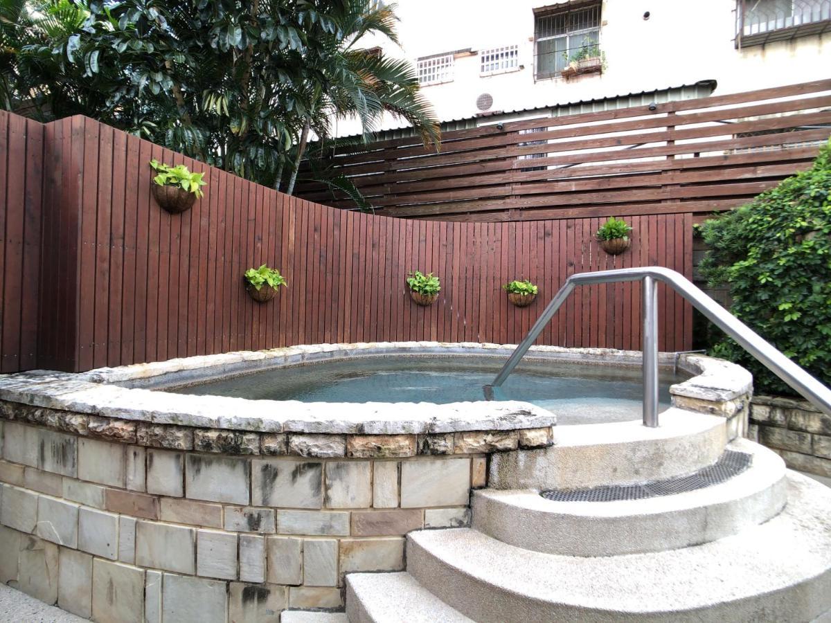Evergreen Laurel Hotel - Taichung Eksteriør bilde The photo shows a small outdoor hot tub or spa area. It's surrounded by a wooden fence, with several planters containing greenery attached to the wall. The hot tub is round, with a stone border, and there are steps leading up to it with a stainless s